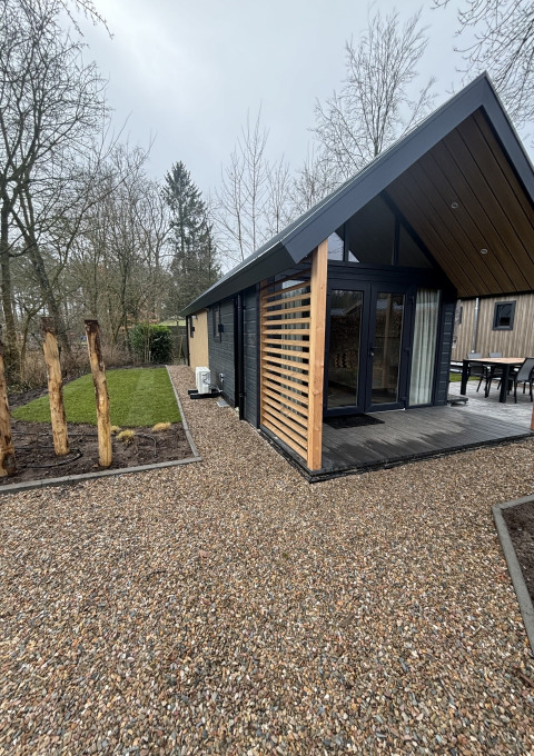 Casa pequeña moderna en Veluwepark de Bosgraaf, Países Bajos, con jardín verde y sendero de grava.