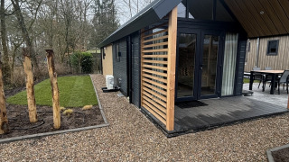 Tiny house moderna al Veluwepark de Bosgraaf nei Paesi Bassi con vialetto di ghiaia e giardino verde.