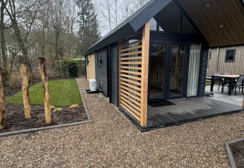 Moderne tiny house ved Veluwepark de Bosgraaf i Holland, med grussti og grønne omgivelser.