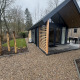 Moderne tiny house ved Veluwepark de Bosgraaf i Holland, med grussti og grønne omgivelser.