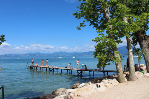 People relax and enjoy the sun on a pier at Camping Cisano/San Vito holiday park in Veneto, Italy.
