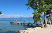 Solrige badegæster på en bådebro ved søbredden i Camping Cisano/San Vito, Veneto, Italien.