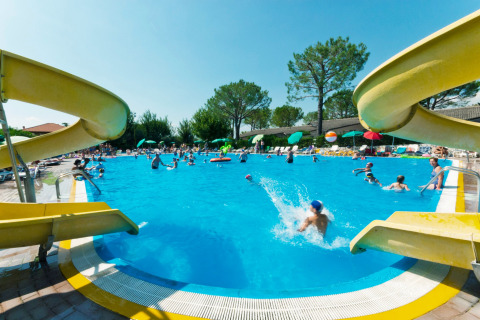 Niños y familias se divierten en la piscina con toboganes acuáticos en Camping Cisano/San Vito, Véneto, Italia.