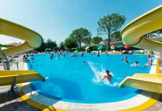 Børn og familier nyder solen og vandrutsjebaner i svømmebassinet på Camping Cisano/San Vito i Veneto, Italien.