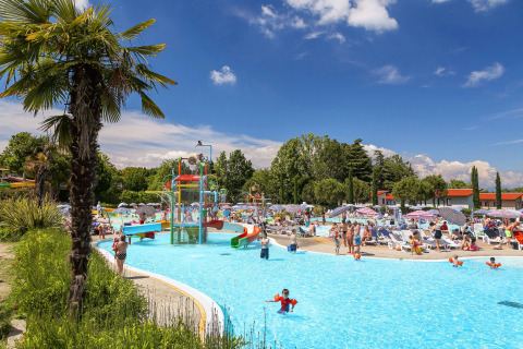 Travl scene ved swimmingpool med vandrutsjebaner og familier på Camping Cisano/San Vito i Veneto, Italien.
