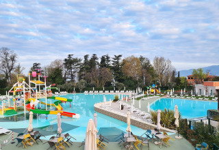 Stor swimmingpool med farverige rutsjebaner og liggestole på Camping Cisano/San Vito i Veneto, Italien.
