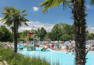Feriepark poolområde med vandrutsjebaner, palmer og mange feriegæster på Camping Cisano/San Vito i Veneto, Italien.