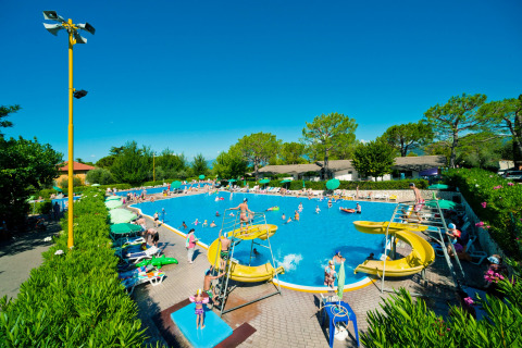 Piscina para familias con toboganes amarillos y tumbonas en Camping Cisano/San Vito, Véneto, Italia.