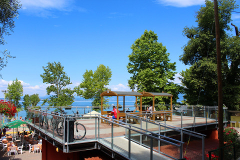 Terrazza su due livelli con biciclette, tavoli e persone al Camping Cisano/San Vito in Veneto, Italia.