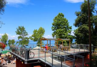 Two-level terrace with bikes, picnic tables, and people at Camping Cisano/San Vito, Veneto, Italy.