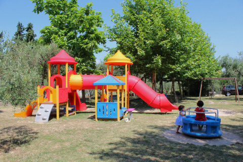 Children playing on colorful playground equipment at Camping Cisano/San Vito holiday park in Veneto, Italy.