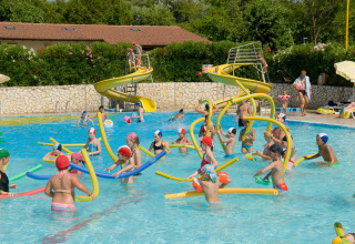 Børn leger med farvede skumrør i en swimmingpool med vandrutsjebaner på en feriepark i Veneto, Italien.