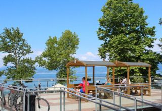 Udendørs siddeplads med udsigt over søen og bjerge på Camping Cisano/San Vito, Veneto, Italien.