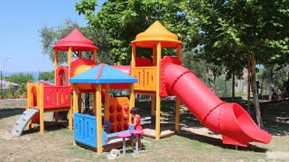 Colorful playground with slides and play structures under trees at Camping Cisano/San Vito, Veneto, Italy.