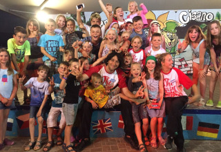 Un grande gruppo di bambini e adulti sorride per una foto al Camping Cisano/San Vito, parco vacanze in Veneto.
