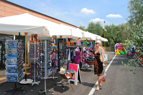Woman shopping at outdoor market stalls at Camping Cisano/San Vito holiday park in Veneto, Italy.