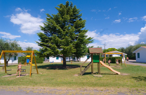 Niños juegan en un parque infantil con tobogán y columpios en Camping Cisano/San Vito, Veneto, Italia.