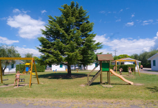 Niños juegan en un parque infantil con tobogán y columpios en Camping Cisano/San Vito, Veneto, Italia.