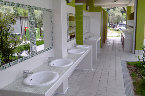 Outdoor washing area with several sinks and mirrors at Camping Cisano/San Vito holiday park in Veneto, Italy.