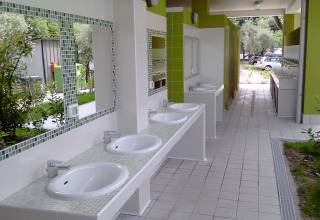 Outdoor washing area with several sinks and mirrors at Camping Cisano/San Vito holiday park in Veneto, Italy.