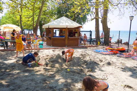 Children play in the sand near a snack bar at Camping Cisano/San Vito holiday park in Veneto, Italy.
