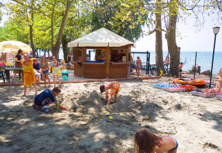 Kinderen spelen in het zand bij een snackbar op Camping Cisano/San Vito vakantiedorp in Veneto, Italië.