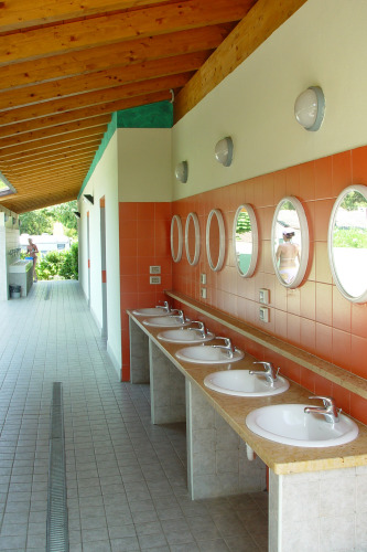 Outdoor washing area with round mirrors and six sinks at Camping Cisano/San Vito, Veneto, Italy.