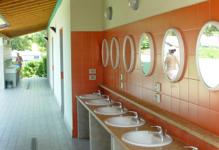 Espace de lavage extérieur avec miroirs ronds et six lavabos au Camping Cisano/San Vito, Vénétie, Italie.