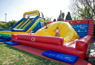 Enfants jouant sur un grand toboggan et château gonflable au Camping Cisano/San Vito, parc de vacances en Vénétie, Italie.