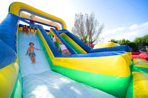 Niños jugando en un gran tobogán inflable al aire libre en el Camping Cisano/San Vito en Veneto, Italia.