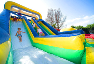 Kinderen genieten op een grote opblaasbare glijbaan bij Camping Cisano/San Vito in Veneto, Italië.