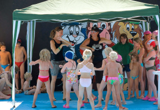 Kinderen doen activiteiten onder een tent in een vakantiepark in Veneto, Italië, begeleid door volwassenen.