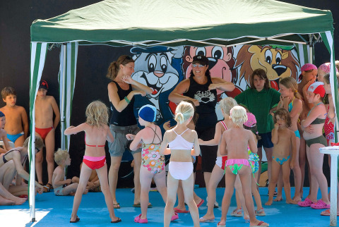 Niños participan en actividades bajo una carpa con adultos en un parque vacacional de Véneto, Italia.