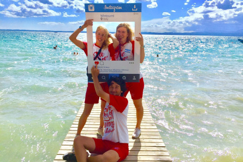 Tres amigos posan con un marco de Instagram en el muelle de Camping Cisano/San Vito, Véneto, Italia.