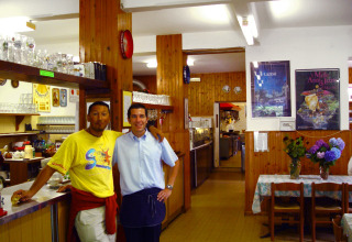 Two men stand in a cozy restaurant at Camping Cisano/San Vito holiday park in Veneto, Italy.
