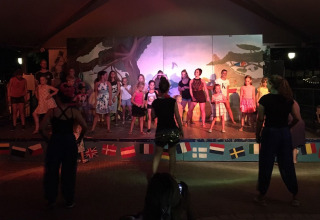 Børn og voksne optræder på en scene om aftenen ved Camping Cisano/San Vito feriepark i Veneto, Italien.