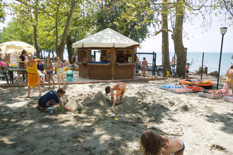 Children play in the sand near a beachfront bar at Camping Cisano/San Vito holiday park in Veneto, Italy.