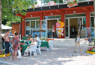 Mensen zitten te eten en ontspannen op het terras van Camping Cisano/San Vito vakantiepark in Veneto, Italië.