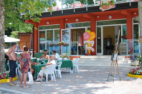 Mensen zitten te eten en ontspannen op het terras van Camping Cisano/San Vito vakantiepark in Veneto, Italië.