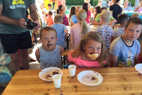 Children participate in a food game at a long table at Camping Cisano/San Vito holiday park in Veneto, Italy.