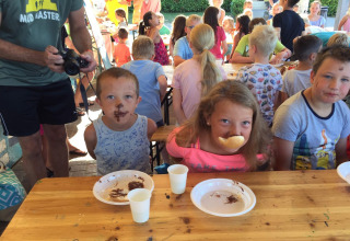 Kinderen nemen deel aan een grappig eetspel op Camping Cisano/San Vito, een park in Veneto, Italië.
