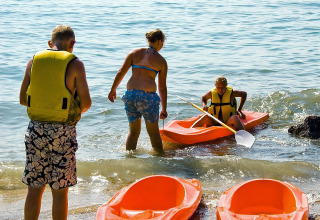Family at the lakeshore in Camping Cisano/San Vito, Veneto, Italy, preparing for kayaking activities.