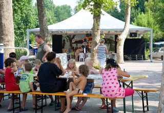 Bambini e adulti si divertono con attività creative ai tavoli all'aperto al Camping Cisano/San Vito, Veneto.