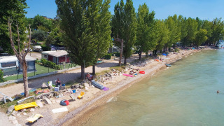Beach with trees and campers at Camping Cisano/San Vito holiday park in Veneto, Italy, aerial view