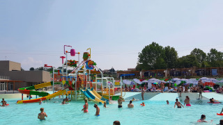 Children playing in a swimming pool with colorful water slides at Camping Cisano/San Vito in Veneto, Italy.
