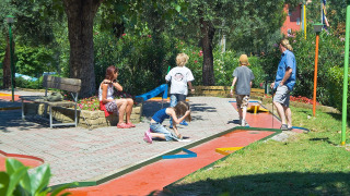 Families enjoy mini golf under the trees at the holiday park Camping Cisano/San Vito in Veneto, Italy.