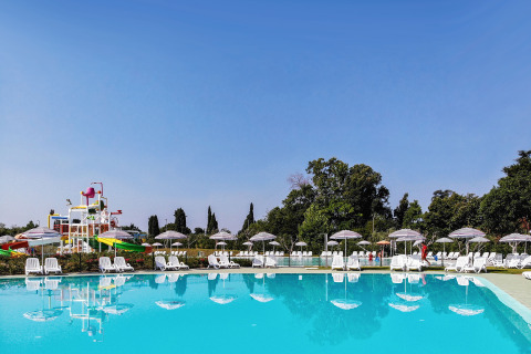 Udendørs swimmingpool med liggestole, parasoller og vandrutsjebaner ved Camping Cisano/San Vito i Veneto, Italien.