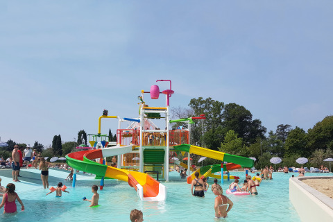 Bambini e adulti si divertono nell’area giochi d’acqua con scivoli a Camping Cisano/San Vito, Veneto, Italia.