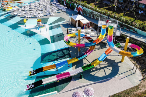 Parco acquatico moderno con scivoli colorati e lettini al Camping Cisano/San Vito in Veneto, Italia.
