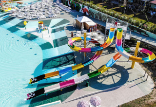 Modern water park with colorful slides and sunbeds at Camping Cisano/San Vito holiday park in Veneto, Italy.